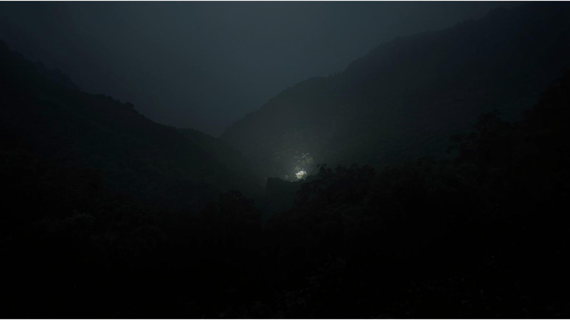 A faint glow held in the depths of a wooded gorge